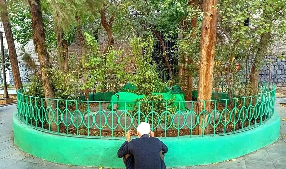  Diyarbakır’ın Sur ilçesinde, Çift Kapı ile Tek Kapı arasında yer alan türbe, yıllardır hem halkın hem de araştırmacıların dikkatini çeken gizemli bir yapıyı temsil ediyor. ''Hindi Baba'' olarak bilinen bu zatın kimliği, günümüze kadar ulaşan farklı rivayetler nedeniyle netlik kazanabilmiş değil.  Şehrin tarihi dokusu içerisinde yer alan bu küçük mezar, yüzyıllardır ziyaret edilen manevi duraklardan biri olma özelliğini sürdürüyor.  Kimi anlatımlara göre, Hindistan’dan Diyarbakır’a gelen bir dervişe ait olduğu ifade edilirken, kimi kaynaklarda ise Akkoyunlu Devleti’nin önemli Türk aşiretlerinden ''Hindî'' aşiretiyle bağlantılı bir şahsiyet olduğu ileri sürülüyor.  KÖKENİ YÜZYILLARDIR TARTIŞILIYOR  1316 (1898) tarihli Diyarbekir Salnamesi’nde ''Hindi Baba Hazretleri’nin Aynüzülal mevkiinde medfun olduğu'' bilgisi yer alıyor.   Bu alan günümüzde Sur ilçesi içinde, İnönü Caddesi üzerinde bulunuyor.  Rivayetlerin bir kısmı, Hindi Baba’nın Hindistan’dan gelen bir derviş olduğunu ve Diyarbakır’da uzun yıllar yaşayarak burada vefat ettiğini aktarır.   Bu anlatıma göre, ''Hindi'' lakabı da ''Hintli'' anlamından gelmektedir.  Buna karşılık başka bir görüş, ''Hindî'' adının coğrafi değil, Akkoyunlu Devleti döneminde etkili olan Türk aşiretlerinden birine ait bir isim olduğunu savunur.   SÜLEYMAN NAZİF’İN AİLESİYLE BAĞLANTI  Bazı kaynaklarda Hindi Baba’nın, ünlü edebiyatçı Süleyman Nazif’in ailesiyle de bağlantılı olduğu ifade ediliyor.  Annesi Ayşe Hanım’ın Akkoyunluların Hindî aşiretine dayandığı ve bu soyun Diyarbakır’da önemli bir yere sahip olduğu belirtiliyor.  Bu bilgiler, Hindi Baba’nın yalnızca bir türbe ismi değil, aynı zamanda Diyarbakır’ın köklü aile yapılarından biriyle ilişkili olabileceği ihtimalini de güçlendirdiği kaydediliyor.  BUGÜN HALA ZİYARET EDİLİYOR  Günümüzde Çift Kapı yakınlarında bulunan türbe, demir parmaklıklarla çevrili halde ziyaretçilerini ağırlamaya devam ediyor. Vatandaşlar burada dua ederken, türbenin manevi bir anlam taşıdığına inanıyor.  Halk arasında anlatılan bir başka rivayet ise türbenin bulunduğu yerdeki mezarın Hindi Baba’ya ait olduğu ve bu alanın yüzyıllardır kutsal kabul edildiği yönünde.  DİYARBAKIR’IN SESSİZ MİRASLARINDAN BİRİ  Hindi Baba’nın kimliği konusunda kesin bir tarihî belge olmamakla birlikte, türbe Diyarbakır’ın yaşayan hafızasında önemli bir yer tutmayı sürdürüyor.   Farklı rivayetlerin iç içe geçtiği bu yapı, şehrin hem tasavvufi hem de tarihî geçmişine ışık tutan sessiz bir tanık olarak varlığını koruyor.